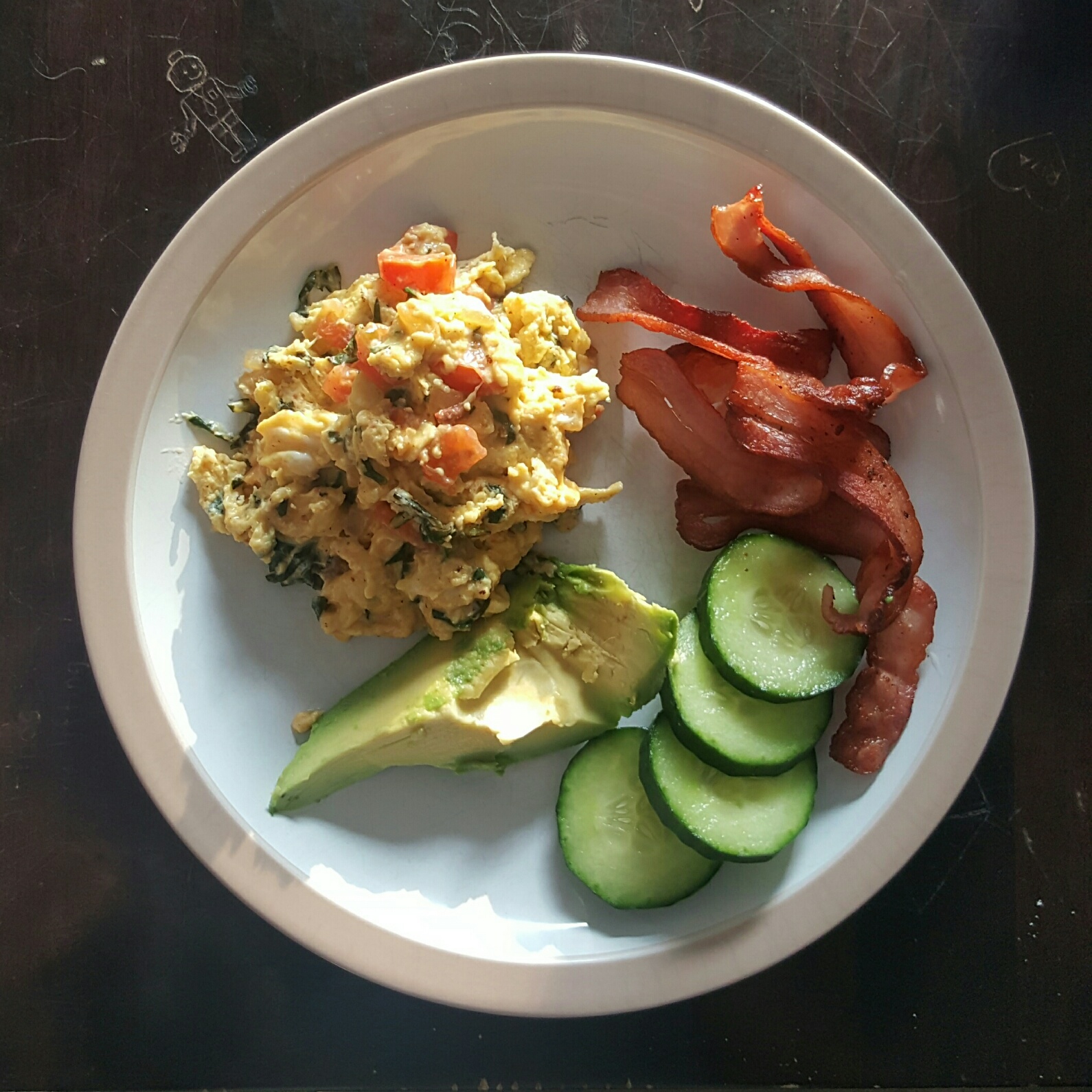 Spinach, tomato and onion scrambled eggs with bacon, cucumber and avo
